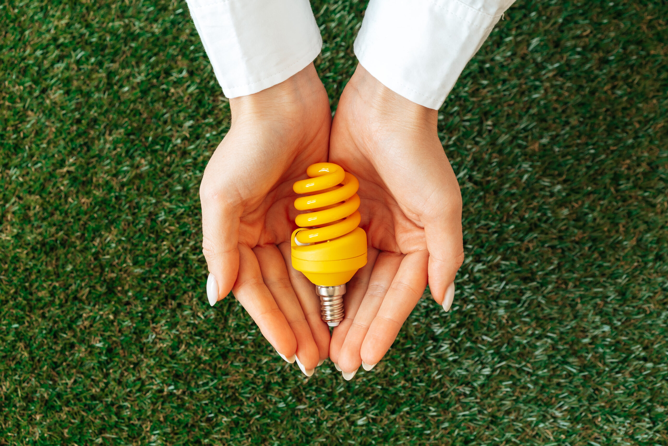 Woman holding lamp in hands above the grass